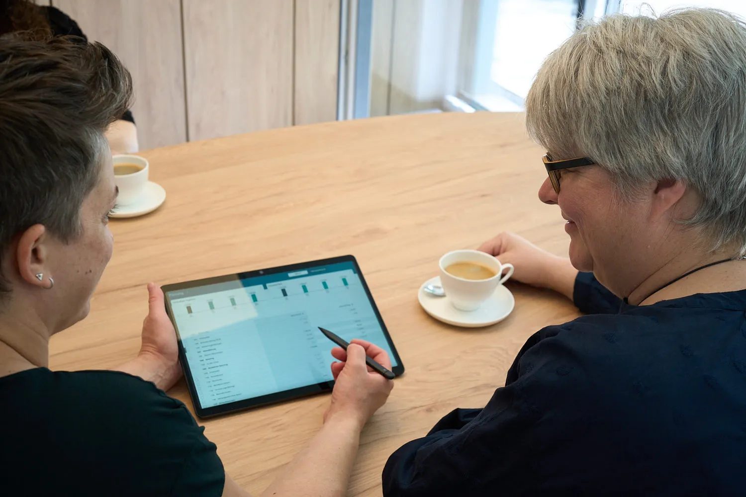 Zwei Mitarbeiterinnen der Steuerkanzlei besprechen eine digitale Auswertung auf einem Tablet
